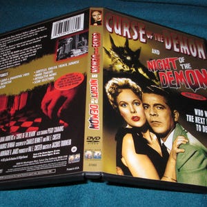 May include: DVD cover art for the horror films "Curse of the Demon" and "Night of the Demon". The cover features a black and white image of a woman and a man with a demonic creature in the background. The text "Who will be the next in line to defy the curse?" is printed on the cover.