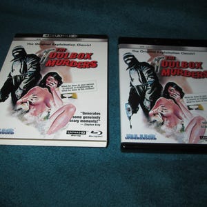 May include: Two Blu-ray cases for the film "The Toolbox Murders". The cases are black and white with a graphic of a masked man holding a tool and a woman in a white dress. The text "The Original Exploitation Classic" is printed on both cases.