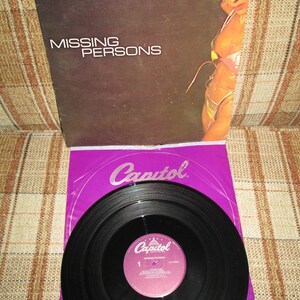 May include: A purple vinyl record with a black record inside. The record is labeled "Capitol" and "Missing Persons".