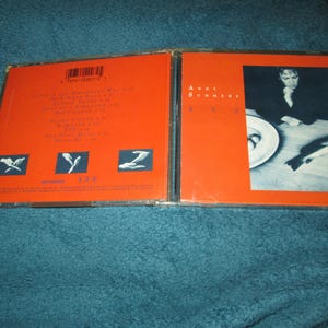 May include: A red CD case with a photo of a person on the front. The text "Andy Summers" and "XYZ" is printed on the front. The back of the case has a list of songs and the text "XYZ".