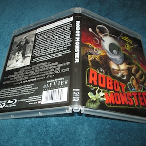 May include: Open Blu-ray case for the film "Robot Monster" in 3D. The cover art features a monster with a robot head and the title in red and yellow. The back has a black and white image and text.