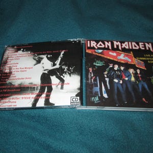May include: Iron Maiden "Live at Summerfest 6/26/81" CD. The album cover features the band members in a live performance setting. The CD case is open, revealing the album art and tracklist. The CD is a music collectible.