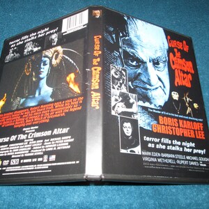 May include: A VHS tape case for the horror film "Curse of the Crimson Altar". The front cover features a black and white image of Boris Karloff and Christopher Lee. The back cover features a black and white image of a woman with a crown of horns. The text on the case reads "Curse of the Crimson Altar", "Boris Karloff", "Christopher Lee", "terror fills the night as she stalks her prey!" and "Mark Eden, Barbara Steele, Michael Gough, Virginia Wetherell, Rupert Davies".