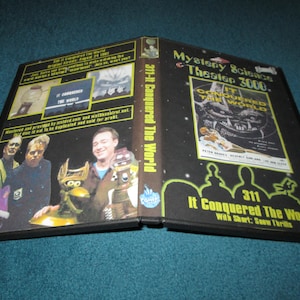May include: Open DVD case for "Mystery Science Theater 3000: It Conquered the World." The cover features a movie poster with a monster and the text "311 It Conquered The World." Inside, images of the cast and movie stills are visible.