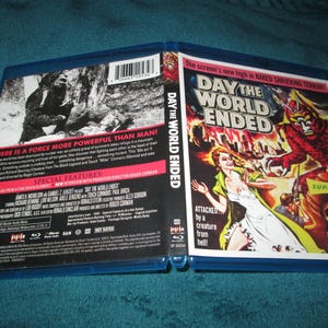 May include: Blu-ray case for the film "Day the World Ended" with a colorful movie poster on the front. The case is open, revealing the disc and additional text. The poster features a woman, a monster, and the text "Superscope."