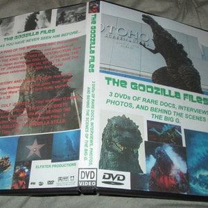 May include: A DVD box set titled "The Godzilla Files" featuring a green Godzilla monster on the front cover. The box set includes 3 DVDs of rare documentaries, interviews, photos, and behind-the-scenes footage.