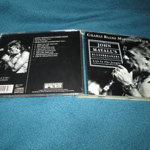 May include: A CD case with a black and white photo of John Mayall on the front. The title of the album is "Charly Blues Masterworks Vol. 4: John Mayall's Bluesbreakers Featuring Walter Trout - Life In The Jungle". The back of the case lists the songs on the album.