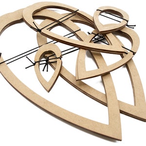Puede incluir: Una escultura abstracta de madera con formas entrelazadas y detalles de cuerda negra. La escultura presenta formas de corazón y de lágrima en un tono de madera natural, creando un efecto tridimensional en capas. El diseño está sobre un fondo blanco.