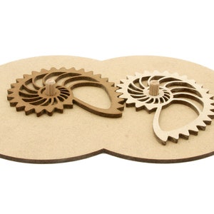 May include: A wooden puzzle with two interlocking gear-shaped pieces, each with a nautilus shell design. The gears are light and dark brown, set on a light brown oval base. The puzzle is designed to interlock and demonstrate mechanical principles.