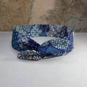Peut inclure: Un bandeau bleu et blanc à motifs noués. Le motif présente des formes géométriques et des motifs floraux.