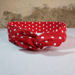 Peut inclure: Un bandeau rouge à pois blancs, noué sur le devant. Le tissu est d'un rouge vif avec des pois blancs espacés régulièrement. Cet accessoire pour cheveux est un ajout élégant à toute tenue.
