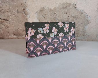 May include: A green and pink fabric wallet with a floral pattern on the top half and a geometric pattern on the bottom half.