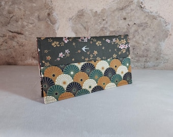 May include: A green and brown fabric wallet with a floral pattern on the top half and a geometric pattern on the bottom half. The wallet has a small bird design on the top half.