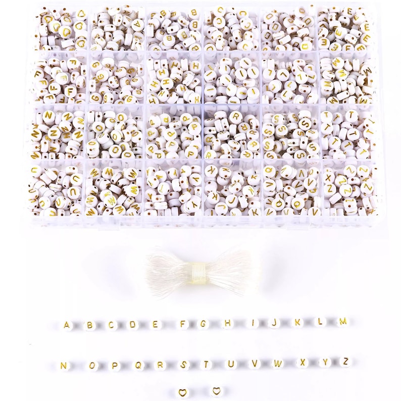 May include: A clear plastic storage box filled with white letter beads with gold lettering. The box has 26 compartments, one for each letter of the alphabet. There is also a spool of white string included.