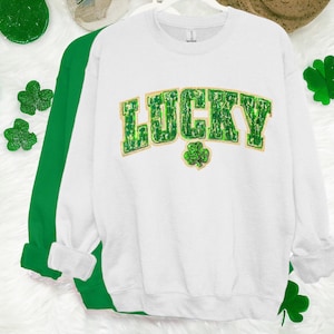May include: White sweatshirt with a green and gold "LUCKY" graphic with a shamrock.