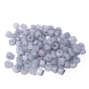 May include: A pile of light blue round beads with a hole in the center. The beads are made of a smooth, polished material.