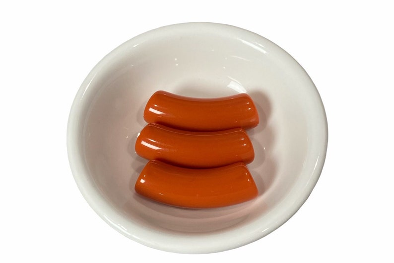 Peut inclure: Trois saucisses de couleur orange dans un bol en c&eacute;ramique blanc.