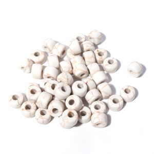 May include: A pile of white ceramic beads with brown marbling. The beads are round and have a hole in the center.