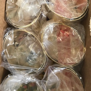 May include: A cardboard box filled with six gold-colored metal bowls. Each bowl is wrapped in clear plastic. The bowls have a simple design with a gold rim and a black band near the base. The bowls are likely for serving or display.