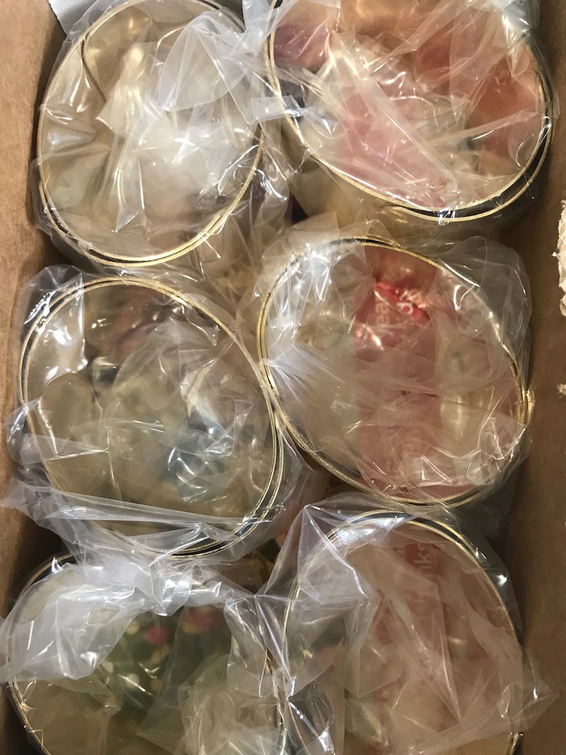 May include: A cardboard box filled with six gold-colored metal bowls. Each bowl is wrapped in clear plastic. The bowls have a simple design with a gold rim and a black band near the base. The bowls are likely for serving or display.