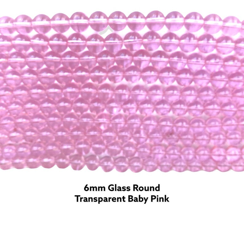 May include: A close-up of a strand of 6mm round glass beads in a transparent baby pink color.