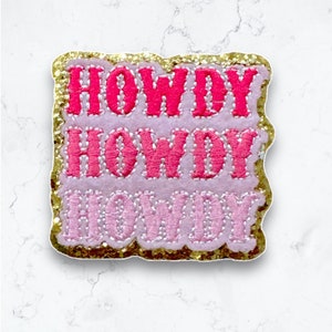May include: A pink and gold glitter iron-on patch with the text "Howdy Howdy Howdy" in a retro font.