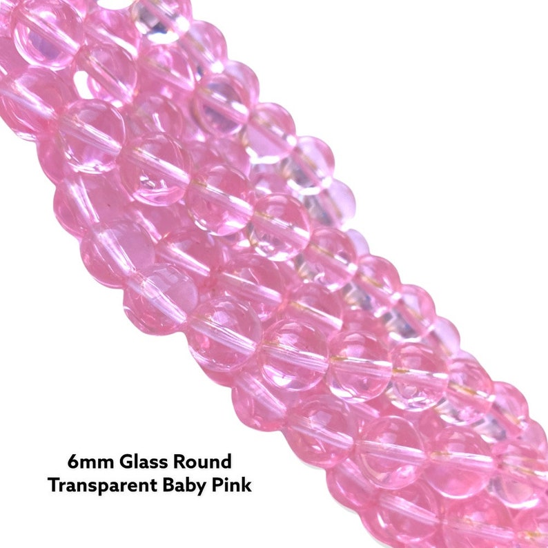 May include: A strand of 6mm round glass beads in a transparent baby pink color.
