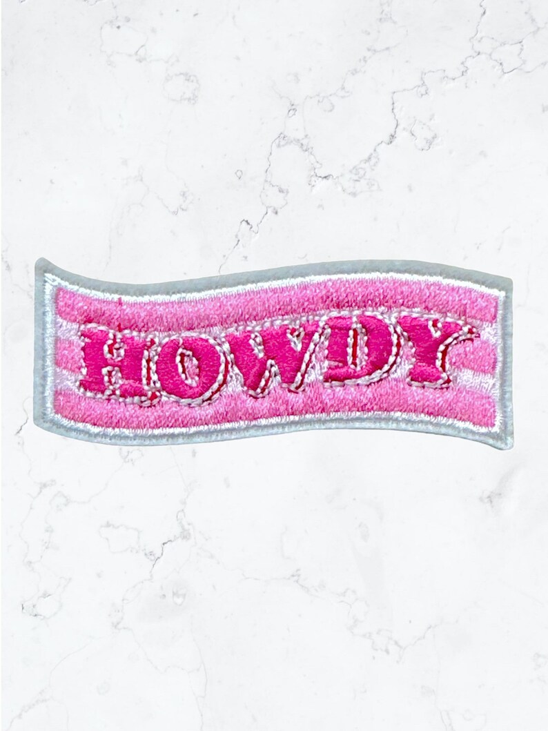May include: Pink embroidered iron-on patch with the word "HOWDY" in a white outline.