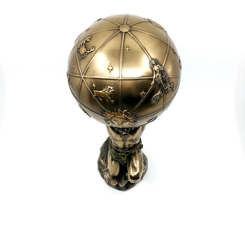 May include: A bronze sculpture of a figure holding a globe with zodiac symbols on it. The globe is gold and has a detailed design.