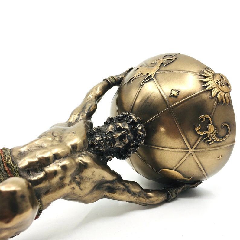 May include: A bronze sculpture of a muscular figure holding up a globe. The globe is decorated with zodiac symbols and constellations.