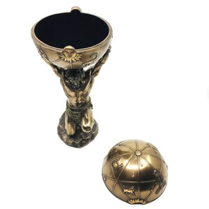 May include: A bronze sculpture of a kneeling man holding a globe with zodiac signs on it. The globe is the lid of a decorative box.