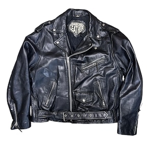 May include: Black leather motorcycle jacket with a notched collar, multiple zippered pockets, and a belt at the waist. The jacket features the text "DIAMOND LEATHER" on a patch near the collar. A classic, durable outerwear piece.