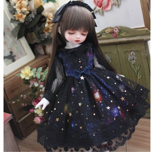 May include: A black and blue doll dress with a galaxy print and gold stars. The dress has a lace trim and a blue velvet bow at the waist.