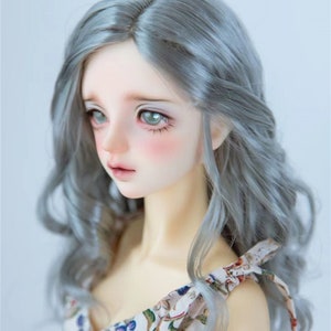 May include: A doll with long, wavy, silver-grey hair wearing a white dress with a floral pattern.
