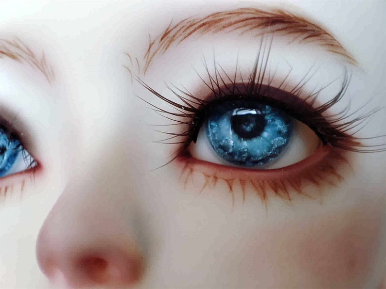 May include: Close-up of a pair of blue eyes with long eyelashes. The eyes are surrounded by a light brown eyebrow and a light pink eyelid.