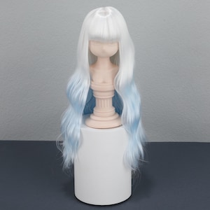 May include: A white wig with long, wavy hair and a blunt bang. The wig has a gradient effect, transitioning from white at the roots to a light blue at the ends. It is displayed on a mannequin head.