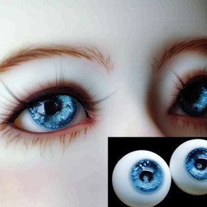 May include: Two blue glass eyes with a white iris and a blue pupil. The eyes are set on a white background.