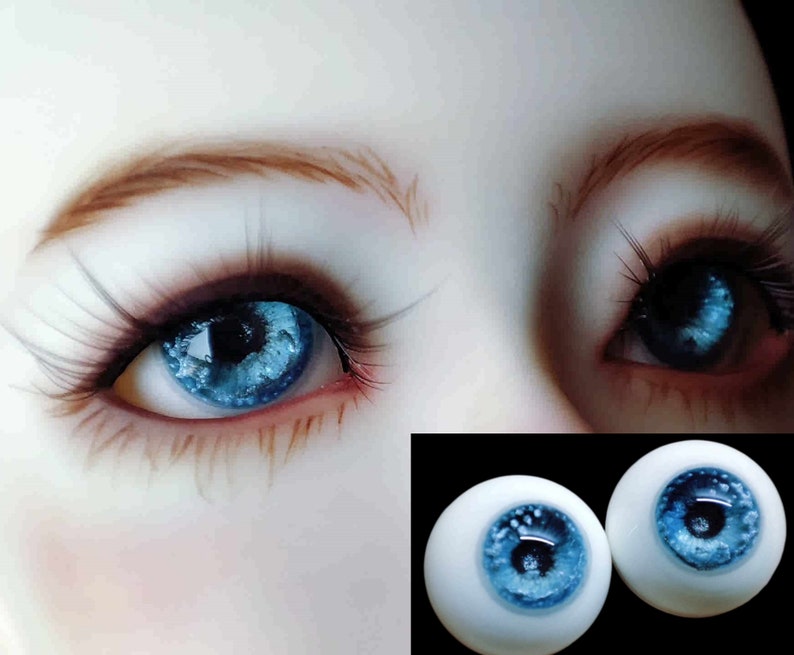 May include: Two blue glass eyes with a white iris and a blue pupil. The eyes are set on a white background.