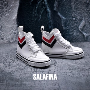 May include: A pair of white high-top trainers with black and red chevron accents. The trainers have white laces and a black rubber sole.