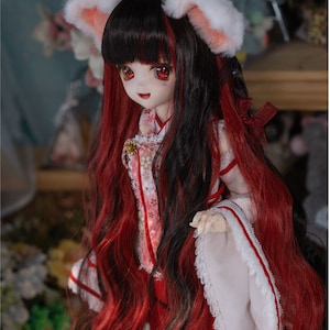 Könnte beinhalten: Eine Puppe mit langen schwarzen und roten Haaren, die ein weißes und rosa Kimono mit einem roten Band trägt. Die Puppe hat weiße, pelzige Ohren auf dem Kopf.