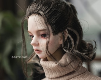 May include: A doll with long, brown hair with streaks of white. The doll is wearing a brown turtleneck sweater.