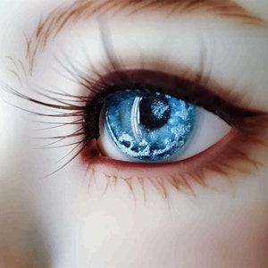 May include: Close-up of a blue eye with a white and blue iris. The eye is surrounded by long eyelashes and a brown eyebrow.