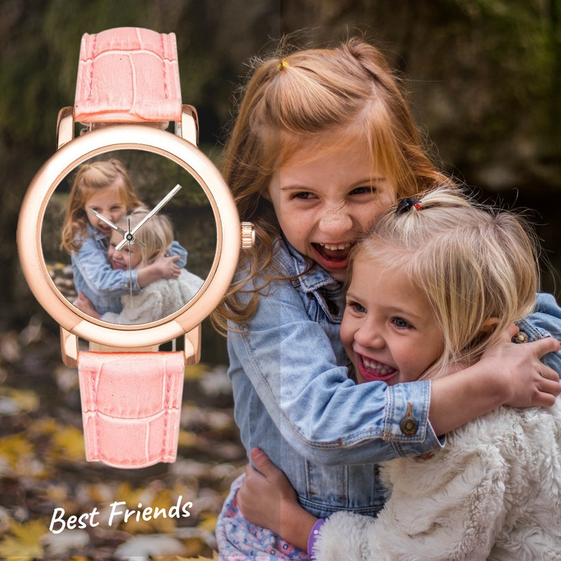 May include: A pink wristwatch with a white face and a picture of two young girls hugging. The watch has a pink leather band with a crocodile pattern. The text "Best Friends" is printed below the watch.