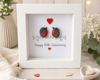 Könnte beinhalten: Ein quadratischer weißer Schattenfugenrahmen mit einem Kieselsteinbild, das zwei Vögel mit roter Brust zeigt. Über den Vögeln befindet sich ein rotes Herz, darunter der Text "Happy 40th Anniversary" mit einem kleinen roten Herz.