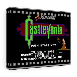 May include: A canvas print featuring the Castlevania video game logo. The design includes the game's title in green and purple, the Konami logo, and the text "PUSH START KEY". The background is black with a film strip border.