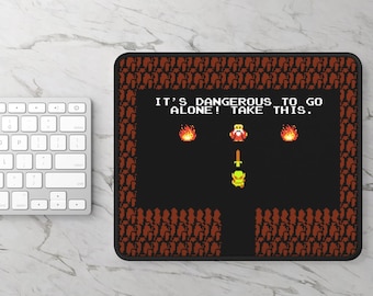May include: A black and red mousepad with a pixelated image of a video game character. The text on the mousepad reads "It's dangerous to go alone! Take this."
