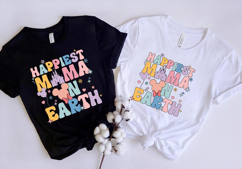 May include: Two t-shirts with the text "Happiest Mama on Earth" in rainbow colors. The shirts feature a cartoon image of Mickey Mouse's head with a castle in the background.