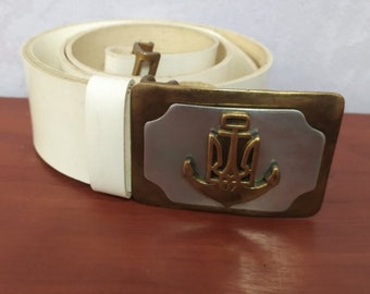 White leather belt with buckle. Fasten the Ukrainian trident with an anchor. New belt for a sailor of the Ukrainian Navy.