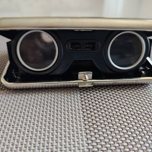 Folding theater glasses. Pocket mini-binoculars in a case. Vintage opera glasses. Theatrical accessories for the eyes. Present. Decor