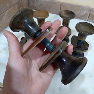 May include: A set of five vintage brown wooden door knobs with a metal screw and a clear plastic handle. The knobs are in various shapes and sizes.